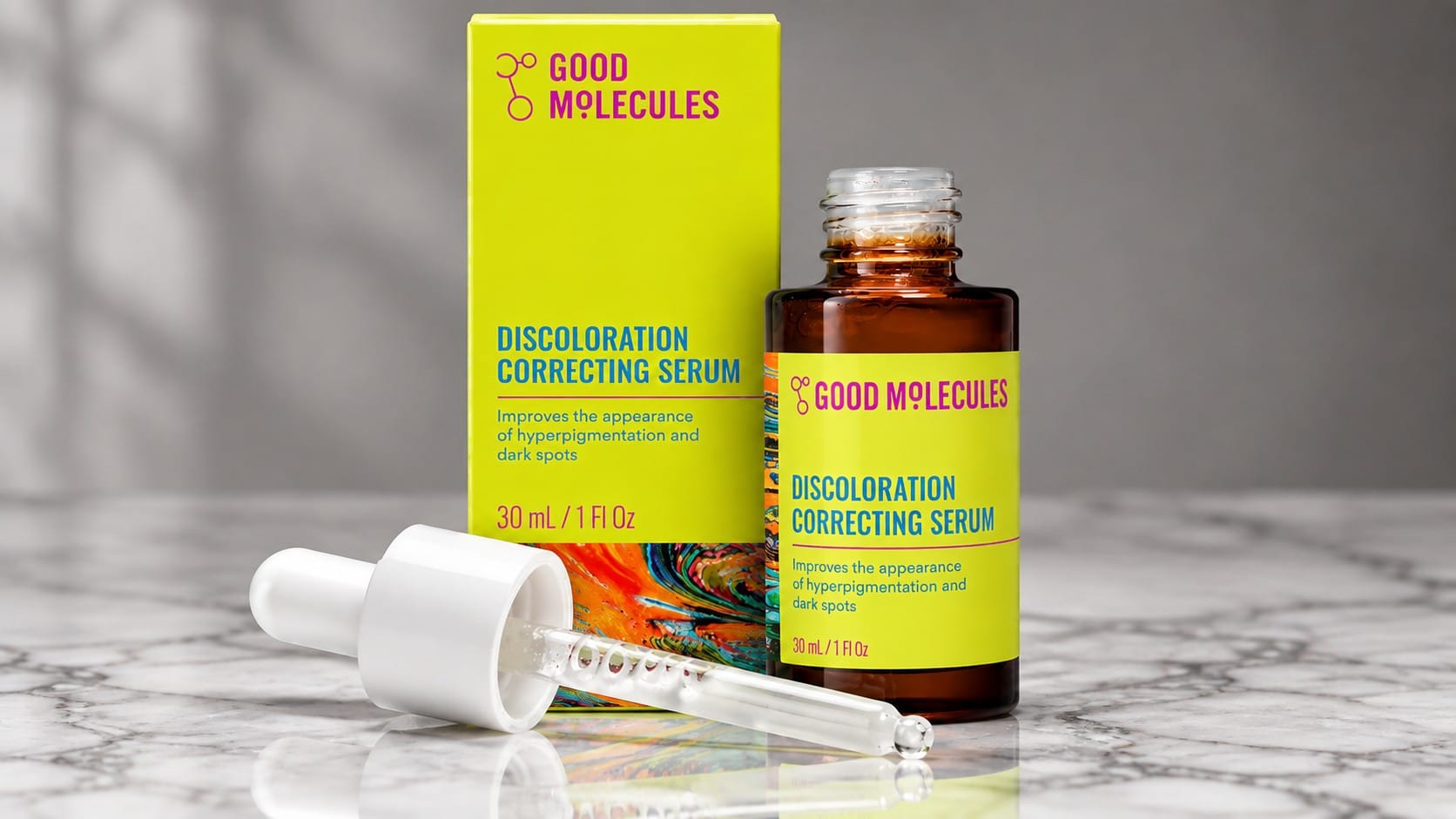 Good Molecules Discoloration Correcting Serum in a 30 mL amber dropper bottle beside its lime-green box, with the glass dropper resting on a marble counter.