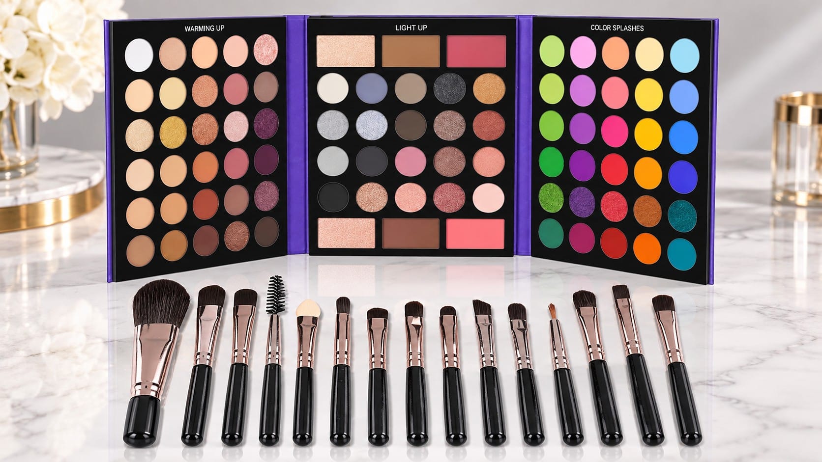 UCANBE 86-color makeup palette open in three panels of matte, shimmer and bright eyeshadows with highlighter, contour and blush, above a row of 15 rose-gold makeup brushes on a marble counter.