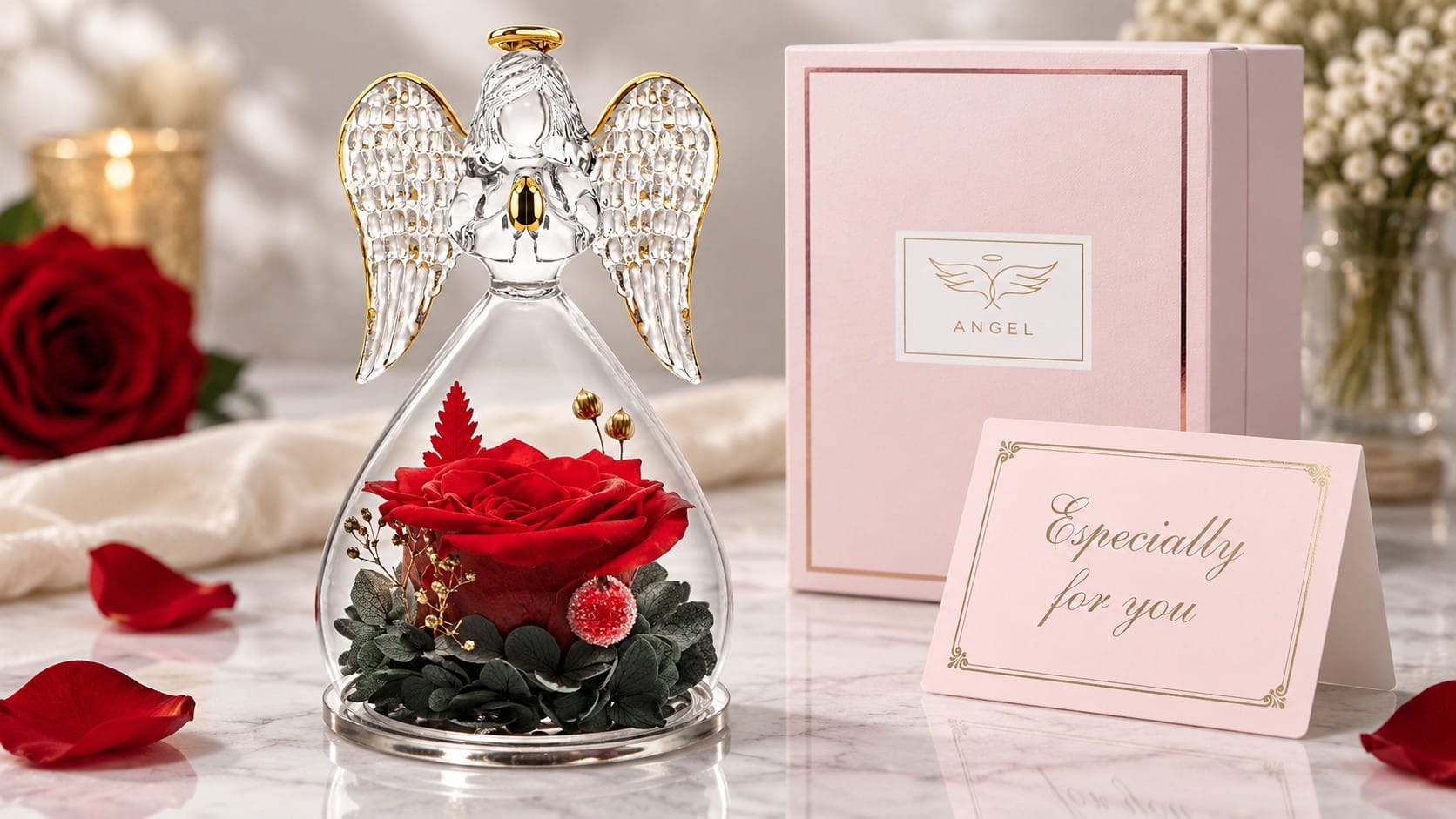 Glass angel figurine with gold-trimmed wings and halo holding a preserved red rose with greenery, beside a pink gift box and an "Especially for you" card on a marble surface with rose petals.