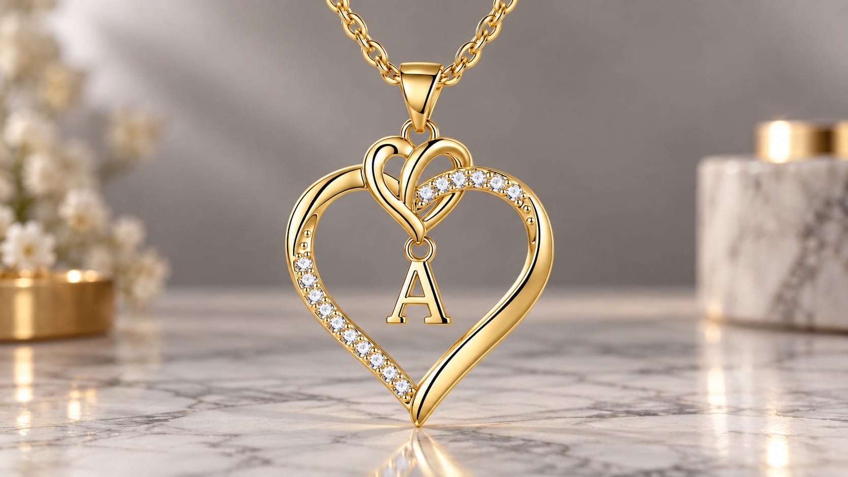 Gold-plated STORUP heart pendant with a dangling letter A initial inside and cubic zirconia accents along one side, on a marble surface with flowers and candles.