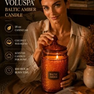 Voluspa Baltic Amber 18 oz candle in an embossed glass jar with a metal lid, lit on a side table