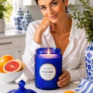 Capri Blue Volcano 19 oz candle in the signature cobalt blue embossed glass jar, lit on a side table