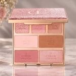Charlotte Tilbury Instant Look in a Palette open on a marble vanity, showing seven numbered pans for eyes, face and cheeks under a glittering pink lid with the CT logo, beside pink roses and a makeup brush.